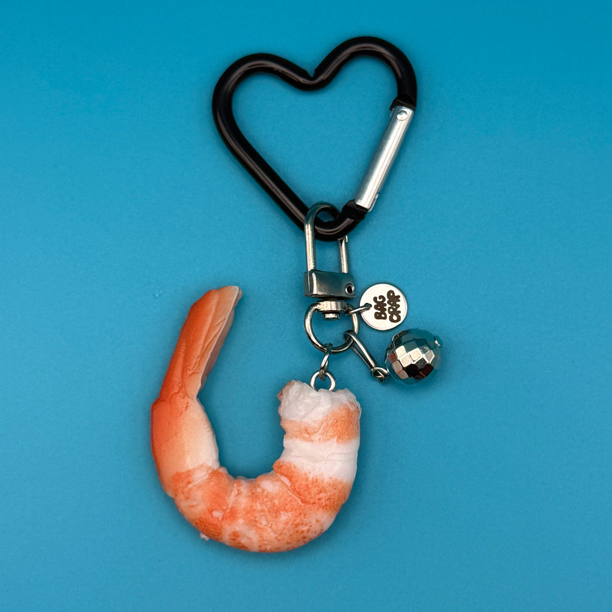 Shrimp-shaped keychain with heart clip on a blue background
