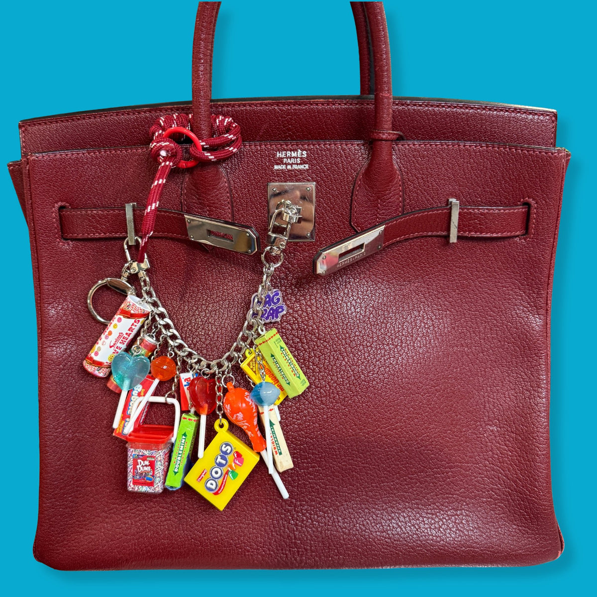 Red handbag with colorful charms in a store setting