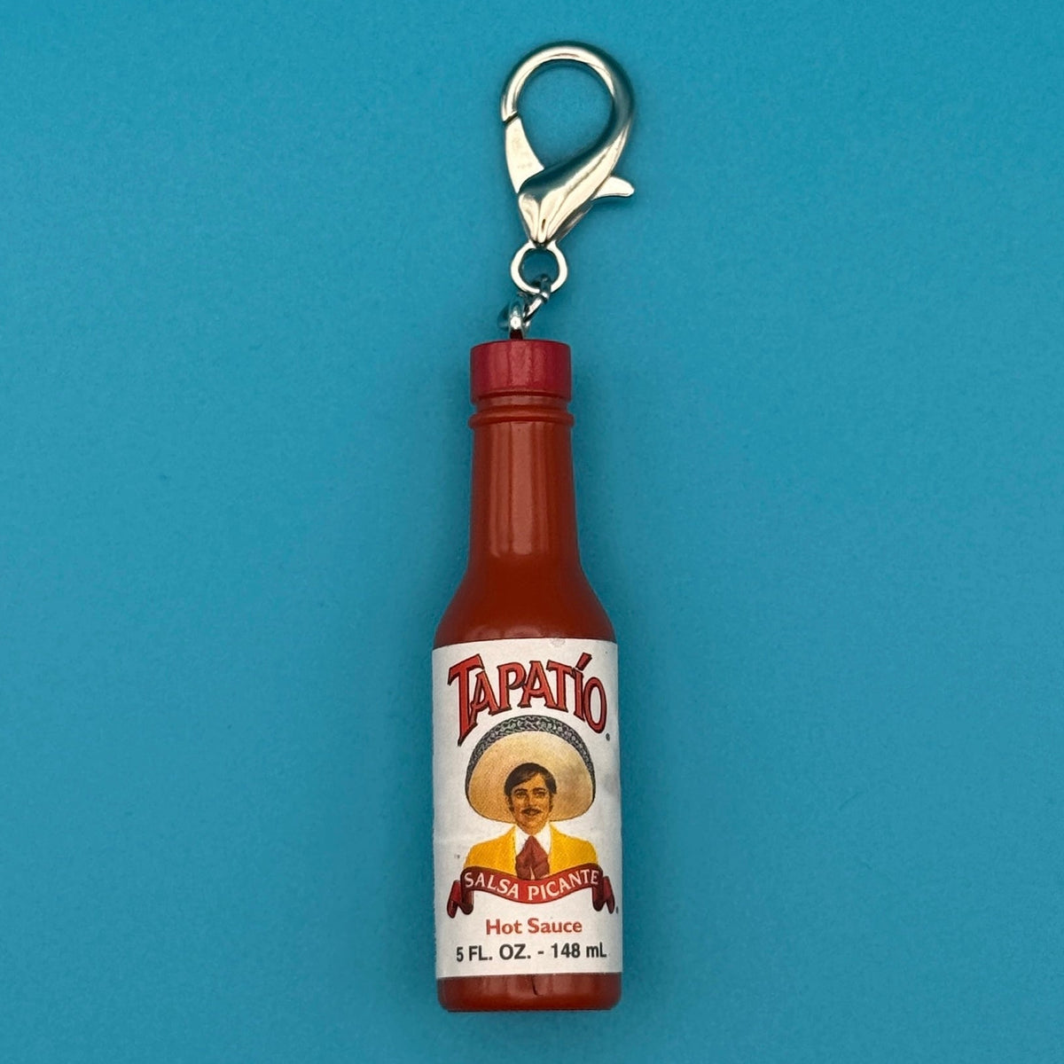 Tapatio hot sauce bottle keychain on a blue background