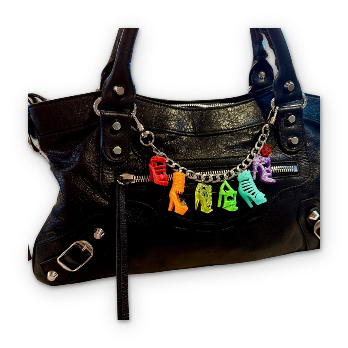 Bag Crap 8 inch silver metal flat curb chain styled with shoe charms on a black leather handbag, white background