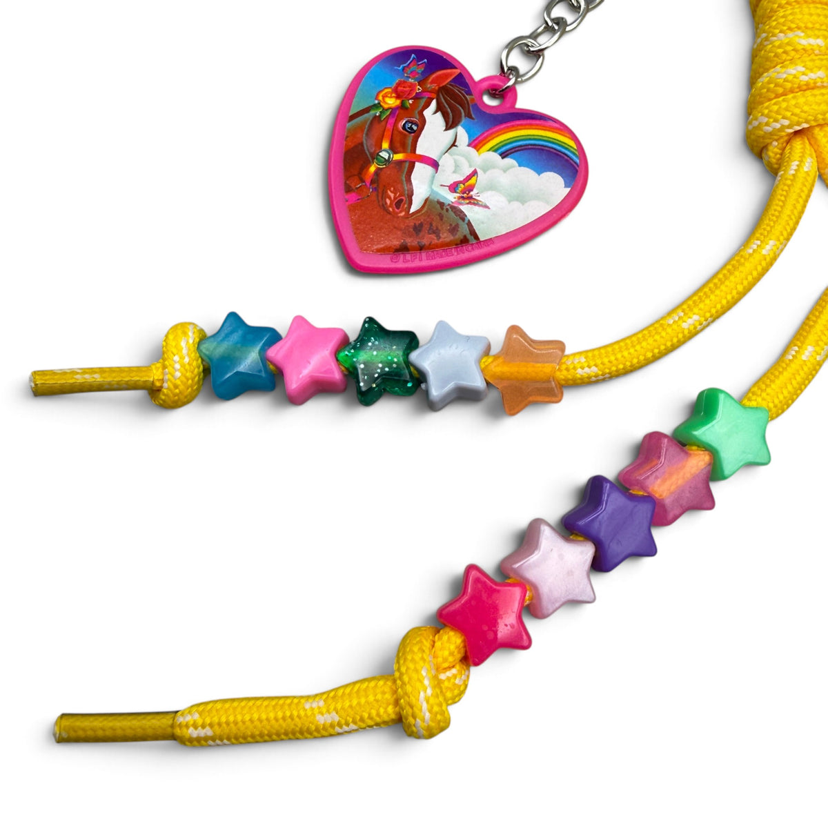 Lisa Frank pink heart horse keychain beside multicolor star beads on yellow paracord