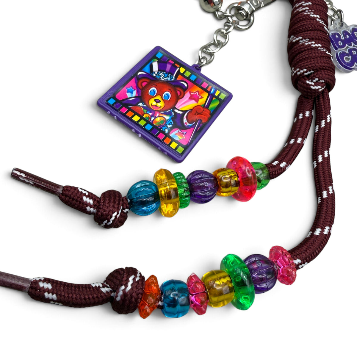 Lisa Frank top hat bear square keychain beside multicolor beads on maroon paracord