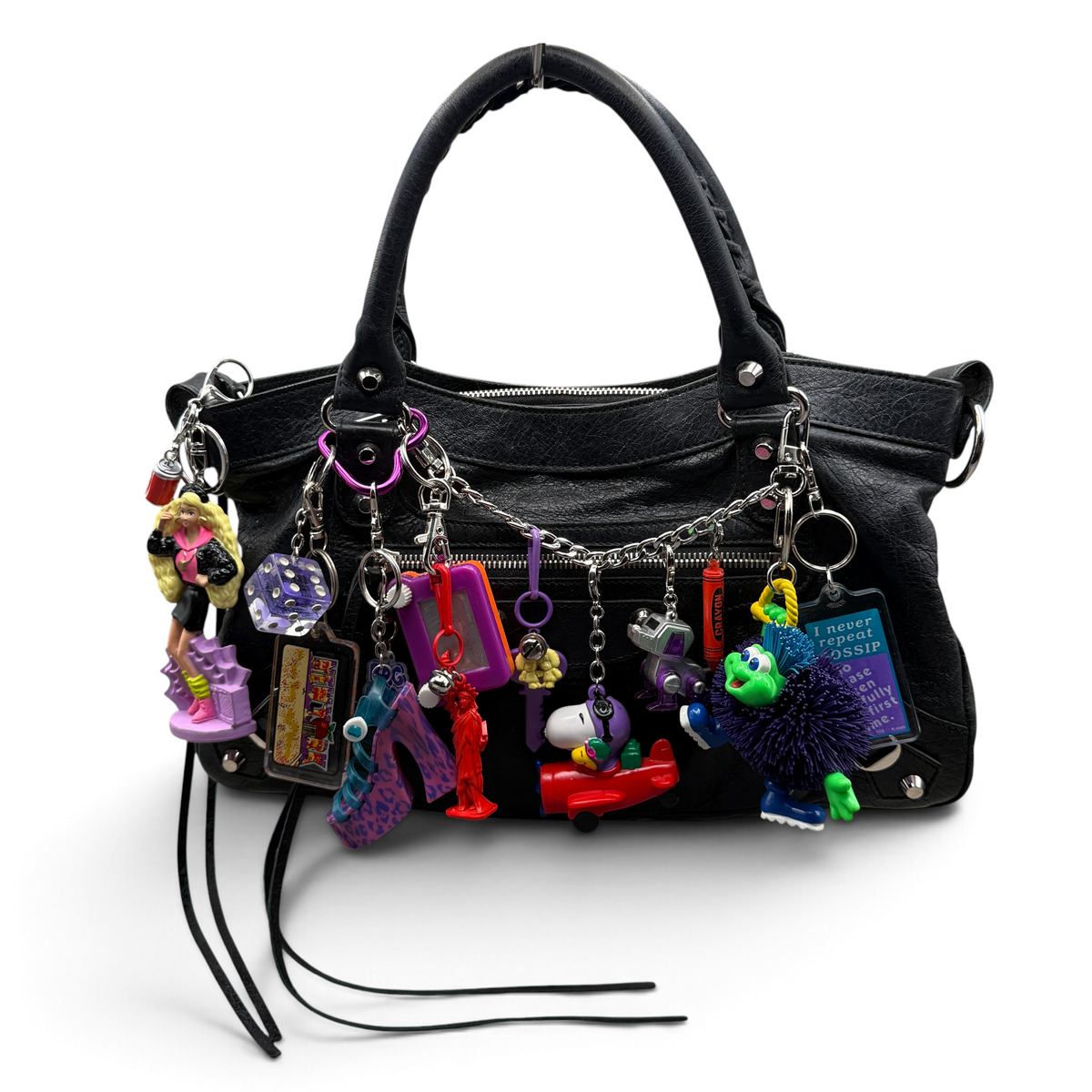 Purple and red charms styled on a black handbag, including Barbie, Koosh Lings T.K., Snoopy airplane and Lisa Frank shoe.