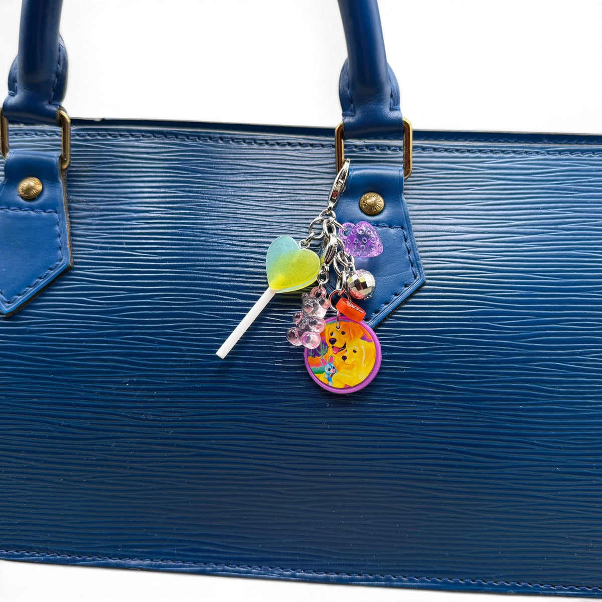 Lisa Frank golden retriever dangle charm clipped to a blue leather handbag