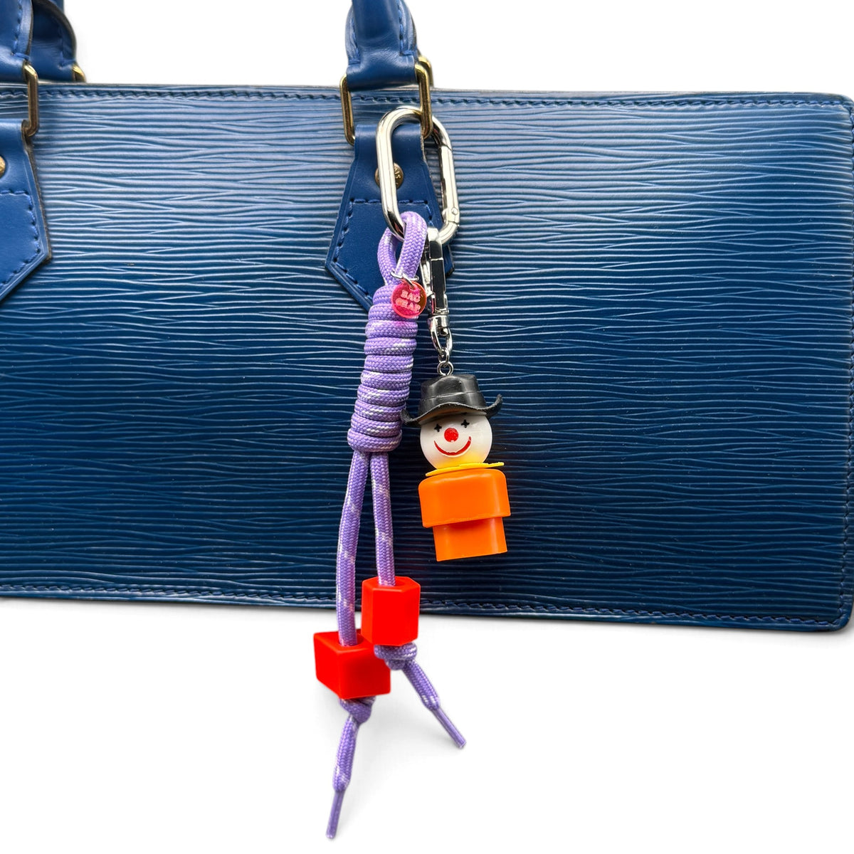 Fisher-Price Little Person clown purple paracord bag charm styled on a blue handbag